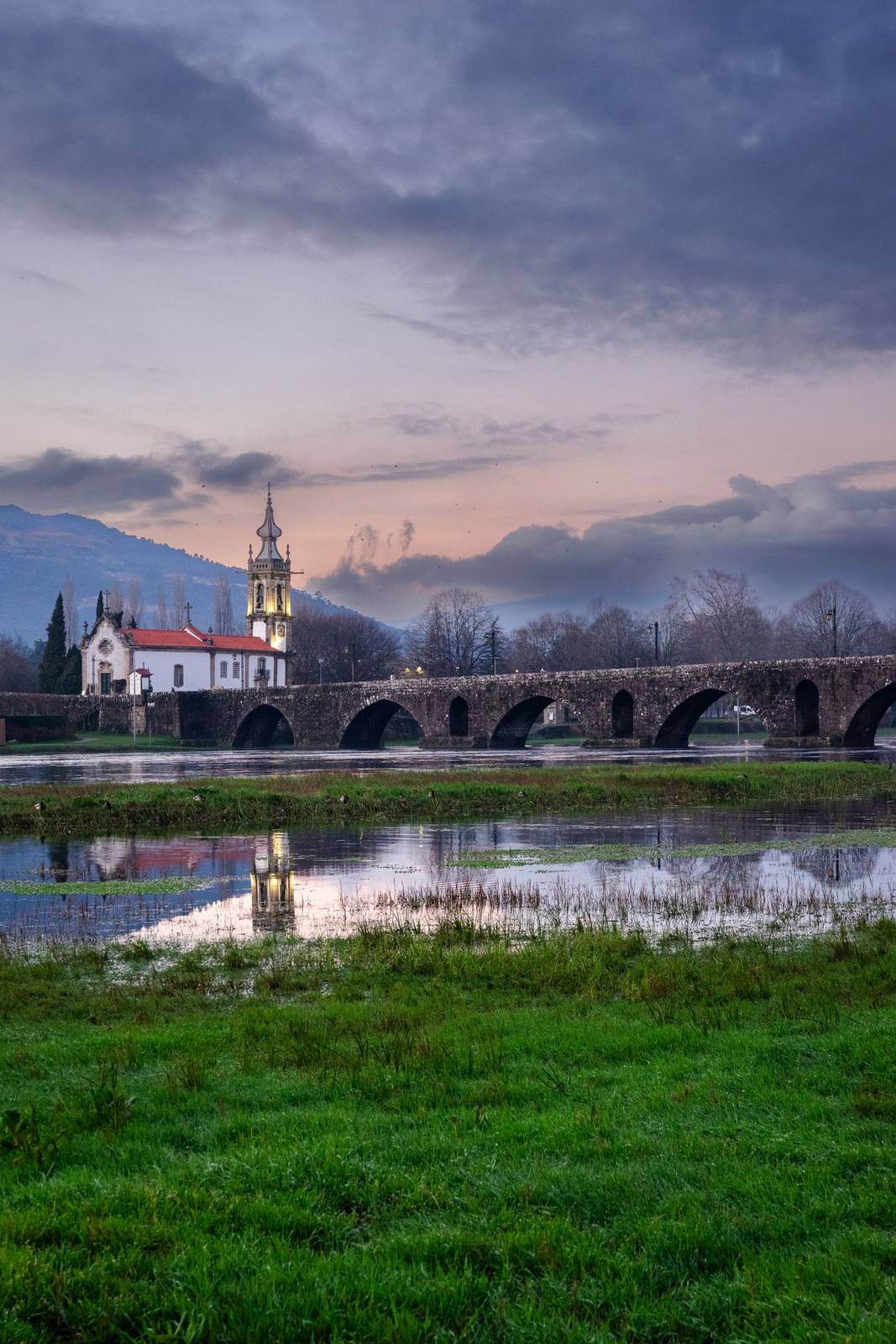 Ponte de Lima and its long arched bridge reflected in the calm Rio Lima at dusk, signature scenery of the Camino Portugues