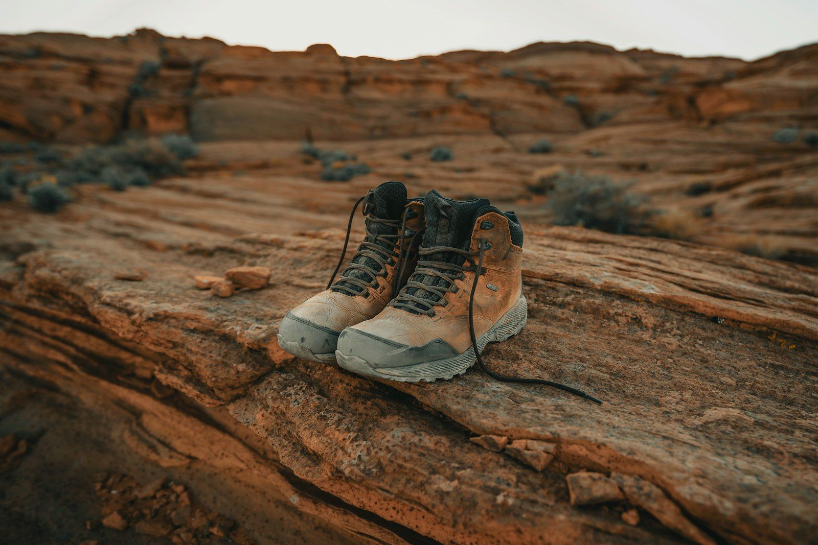 Pair of well-worn brown leather hiking boots resting trailside after a long walk