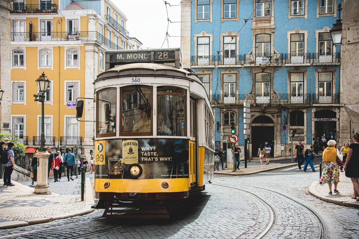 Classic yellow tram running past white buildings on a Lisbon street, starting point of the Camino Portugues from Lisbon