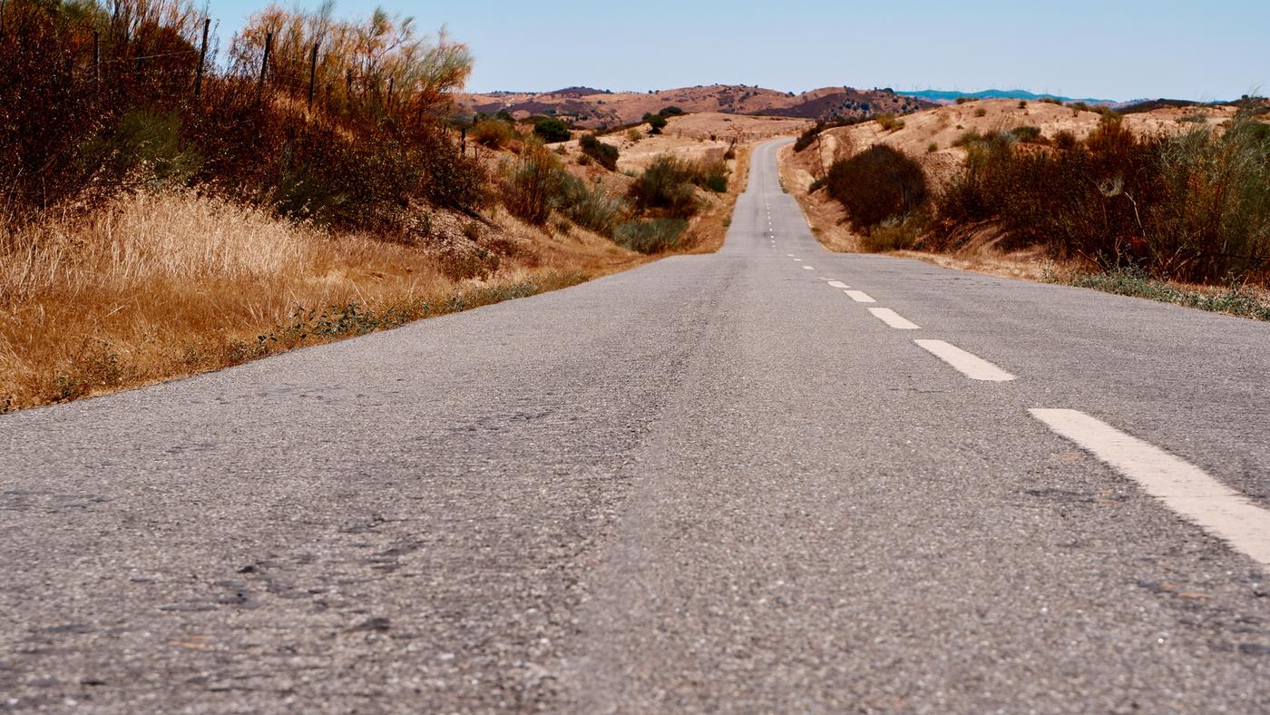 Long straight road stretching to the horizon through open Portuguese countryside