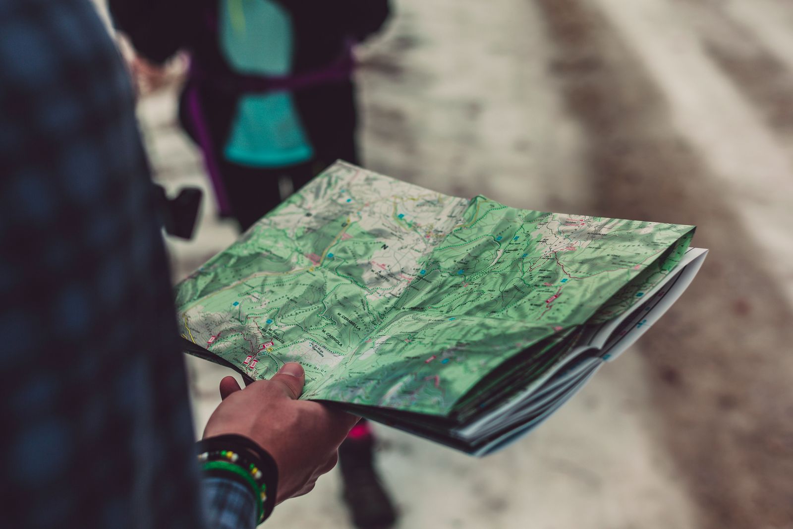 Walker holding a folded paper map with marked routes, backup navigation for the Camino Portugues