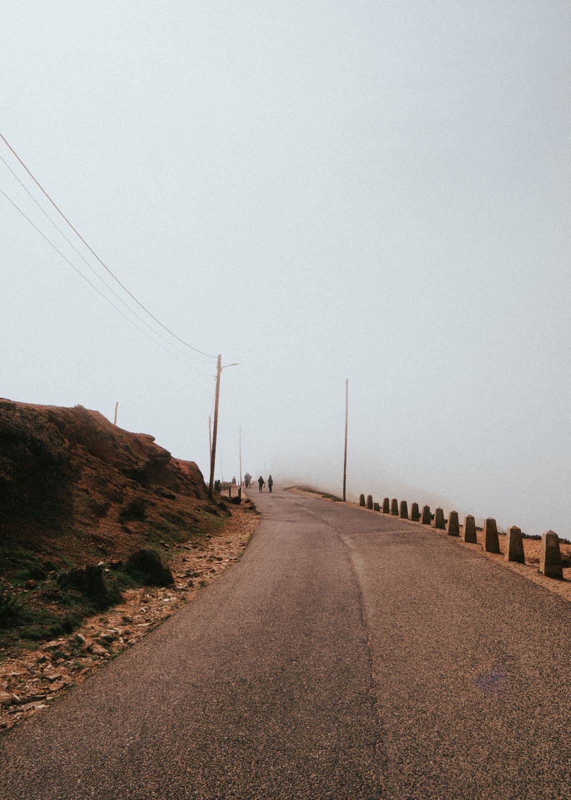 Empty rural road disappearing into morning fog near Nazare, typical quiet stretch between Lisbon and Porto