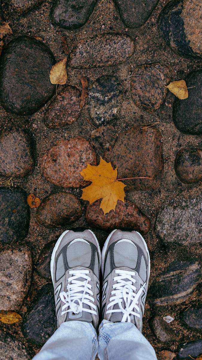 Walking shoes on a leaf-strewn cobblestone path, the surface your footwear must handle on the Camino Portugues